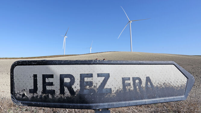 Señal indicadora del municipio de Jerez con los molinos de viento gigantescos del parque eólico El Barroso al fondo.