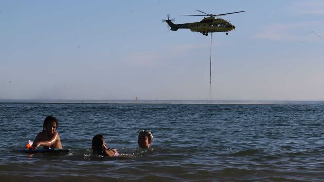 Un helicóptero coge agua del mar para apagar el incendio en El Portil, en imagen de archivo.