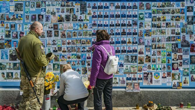 Una pareja deposita flores ante el memorial por los caídos en la defensa de Ucrania, en Kiev.