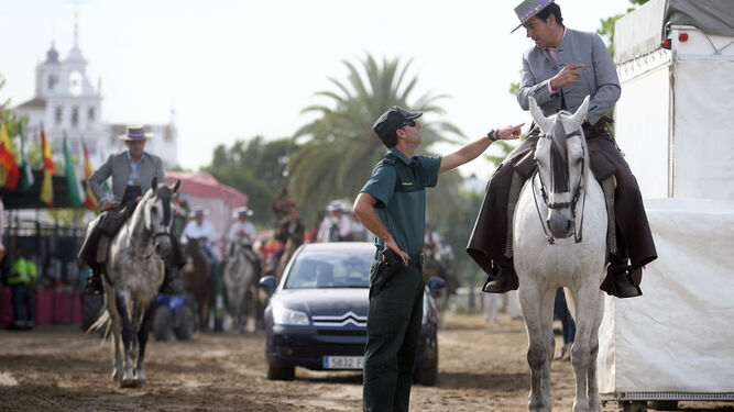 Un agente de la Guardia Civil habla en El Rocío con un peregrino a caballo.