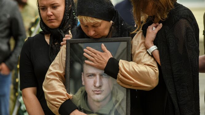 La madre de un soldado ucraniano abraza el retrato de su hijo durante su ceremonia fúnebre.