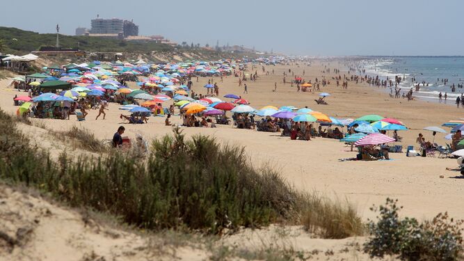 Playa atestada de personas disfrutando del sol y el baño en el mar