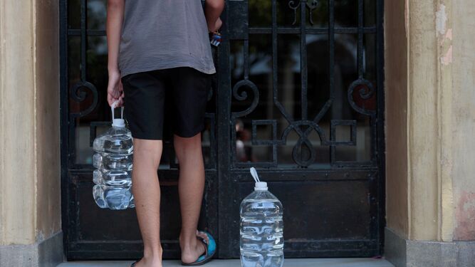 Un joven lleva agua embotellada hasta su casa