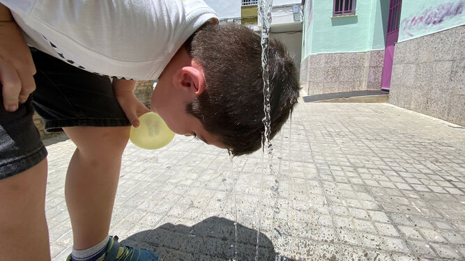 Un niño se refresca la cabeza con agua en la barriada de La Granja, en Jerez
