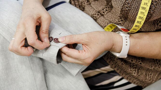 Una modista cose un botón en la manga de un traje de comunión.