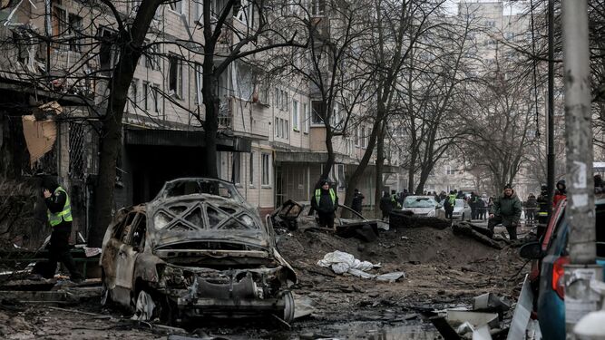 Agentes inspeccionan un vehículo destruido en una zona residencial de Kiev tras un ataque ruso.