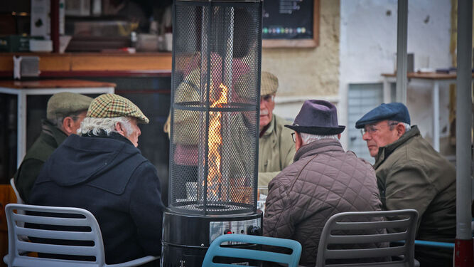 Varios hombres conversan en la terraza de un bar de Jerez al calor de una estufa