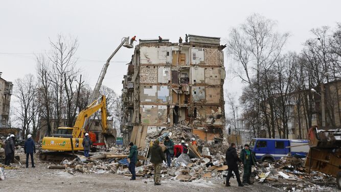 Operarios ucranianos limpian escombros en un edificio destruido por los ataques rusos en Jarkov.
