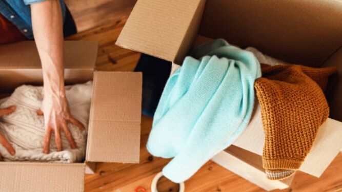 Una persona embala cajas con diferentes prendas de ropa a las que darle un segundo uso
