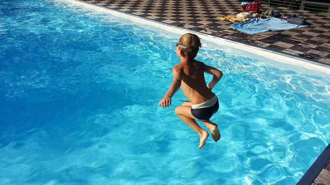 Un niño tirándose a una piscina.