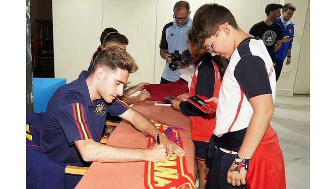 El jugador del Cádiz Robert Navarro firma una bufanda a un joven aficionado.