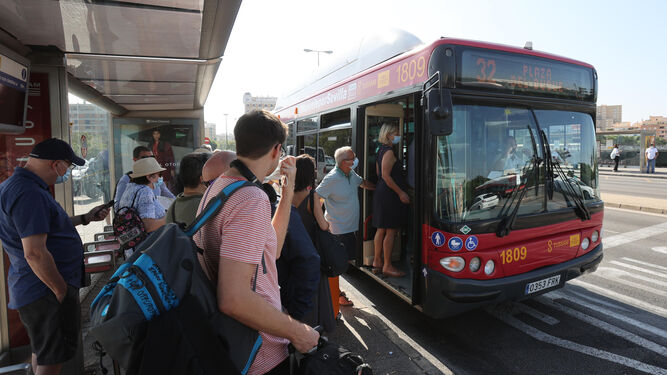 Varias personas hacen cola en una parada de Tussam para subirse a un autobús el pasado verano.