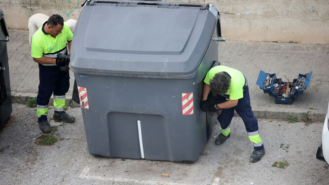Trabajadores del servicio de limpieza reparan un contenedor.