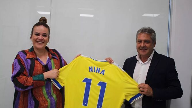 Nina Alemania posa con Pepe Mata sosteniendo ambos una camiseta del equipo.